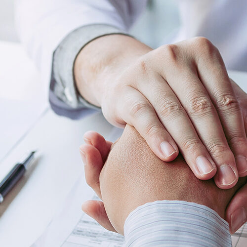 Doctor is holding the patient's hand and giving hope about treating the symptoms of the disease.